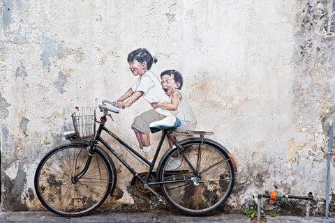 Bicycle in front of house wall with children painted as if they are riding the bike
