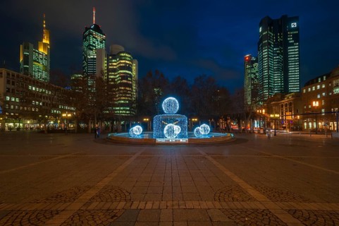 Illuminated Lucae Fountain on Opernplatz square in front of illuminated high-rise skyline