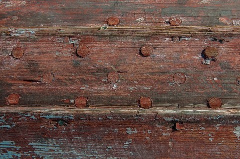 Weathered planks of a boat with residues of red paint