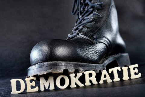 Combat boot standing on the word 'Demokratie'