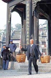 Man shouldering bamboo baskets in front of the Kuixingge Pagoda