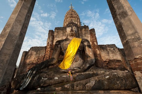 Seated Buddha statue in front of a chedi
