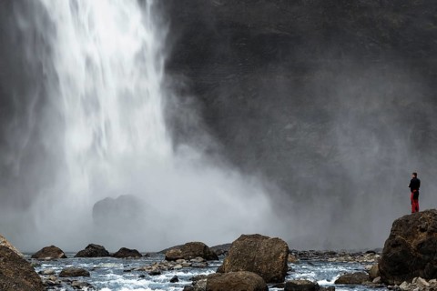 A tourist is standing at the Haifoss waterfall on the Fossa i Thjosardal river