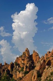 The typical bizarre red rocks of the Calanche of Piana below a blue sky and some clouds. The Calanche of Piana is in the western part of the island Corsica
