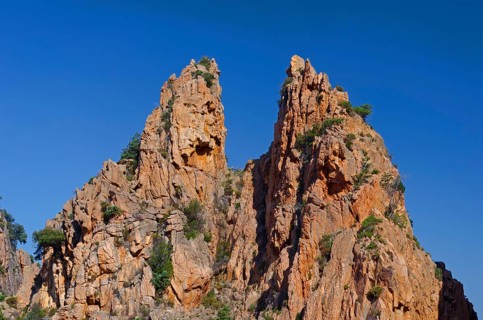 The typical bizarre red rocks of the Calanche of Piana below a blue sky. The Calanche of Piana is in the western part of the island Corsica