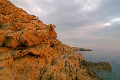 The red granite rocks of the island Ile de la Pietra near L'Ile-Rousse illuminated by the first light of the day. L'Ile-Rousse is in the department Haute-Corse