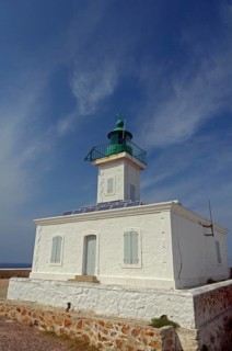 The white lighthouse on the island Ile de la Pietra near L'Ile-Rousse below a blue sky with some clouds. L'Ile-Rousse is in the department Haute-Corse