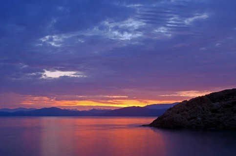 The rising sun forms sun beams behind the rocks of the island Ile de la Pietra near L'Ile-Rousse. L'Ile-Rousse is in the department Haute-Corse