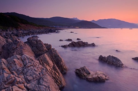Sunrise behind the mountains of Corsica near Ajaccio with the rocky mediterranean coast on the foreground. Ajaccio is the capital of the mediterranean island of Corsica