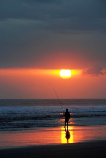 Fisherman fishing at sunset on the beach