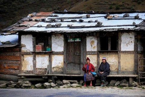 Two Bhutanese women sitting in front of a small shop on the roadside