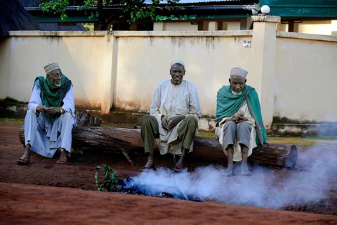 Three men sitting on the roadside in the village of Idool and supervising a fire