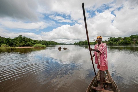 Man steering a pirogue on the Moa River at Tiwai Island Wildlife Sanctuary