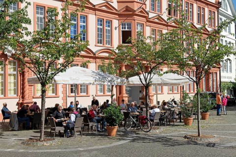 People sitting in front of the older part of the Gutenberg Museum