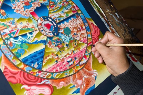 Artist painting a colorful Thangka in one of the art schools near Boudnath Stupa