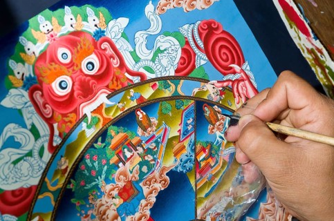 Artist painting a colourful Thangka in an art school