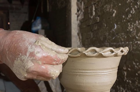Man making pottery by hand with simple equipment