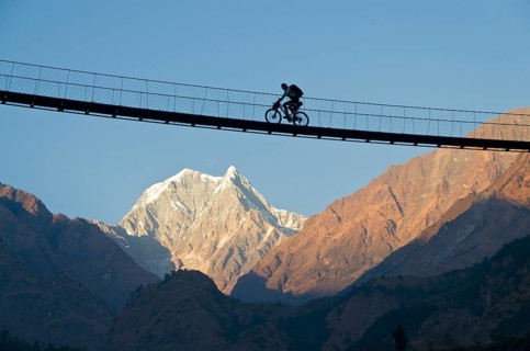 Cyclist crossing a suspension Bridge over Kali Ghandaki Valley