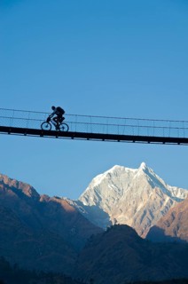 Cyclist crossing a suspension Bridge over Kali Ghandaki Valley