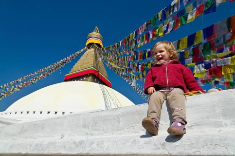 Little tourist child sitting at the foot of Boudnath Stupa