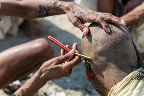 Pilgrim having his head shaved during Kumbha Mela