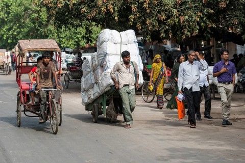 A cycle rickshaw and a man transporting goods on a hand cart on Khari Baoli Road
