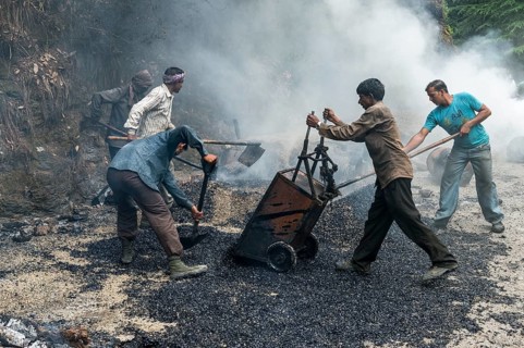 Workers applying hot asphalt to a road at a construction site