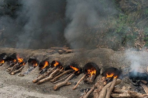Gravel and hot tar being mixed on open fires at a road construction site