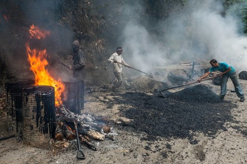 Workers applying hot asphalt to a road at a construction site