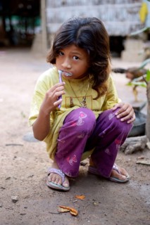 Girl brushing her teeth outside a house