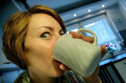 Young woman drinking coffee enthusiastically