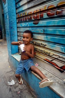 Boy eating from a tub of ice cream in a slum or favela