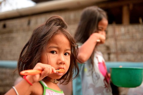 Two girls brushing their teeth outside a house