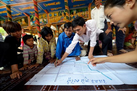 Men and women from the village discussing with representatives of a charity organization