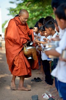 Children donating food and money to a Buddhist monk