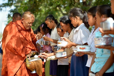 Children donating food and money to a Buddhist monk