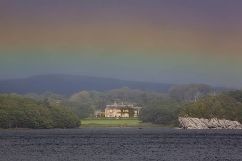 Muckross House on Muckross Lake with rainbow colors in the sky