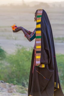 Ahir woman in traditional colorful clothes pouring water at sunet