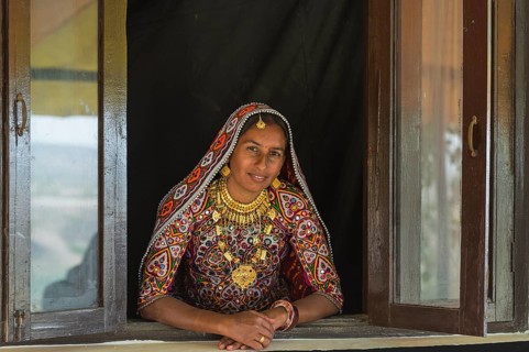Ahir woman in traditional colorful clothes looking out of a window