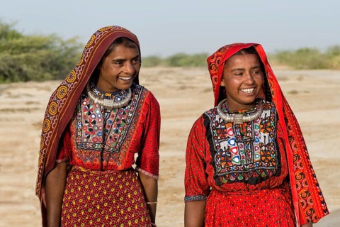 Two Fakirani women in traditional colorful clothes smiling
