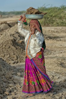 Fakirani woman in traditional colorful clothes carrying earth on her head for road works