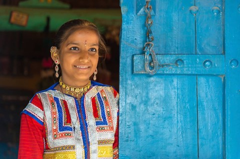 Young girl in traditional colorful clothes standing in a door