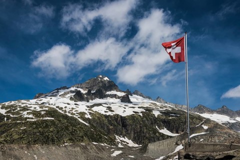 Swiss flag flying in front of Mount Galenstock from the Furka Pass with the Rhone Glacier