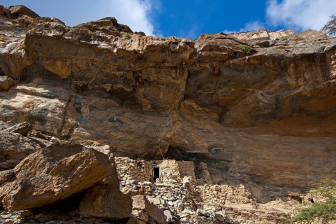 Stone huts of the abandoned settlement of Sap Bani Khamis under a ledge in the Grand Canyon of Oman in the Wadi at Nakhar