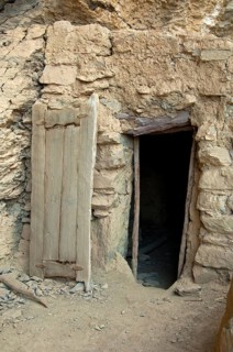 Entrance with a carved wooden door to a stone hut at the abandoned settlement of Sap Bani Khamis under a ledge in the Grand Canyon of Oman in the Wadi at Nakhar