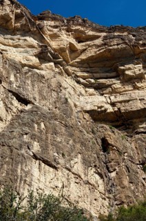 Rock face at the western flank of the Grand Canyon of Oman in the Wadi at Nakhar with hikers on the fixed climbing route leading to the exit from the gorge