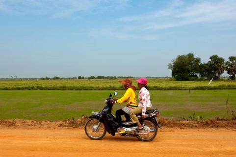 Two women riding on a motorcycle on a country road