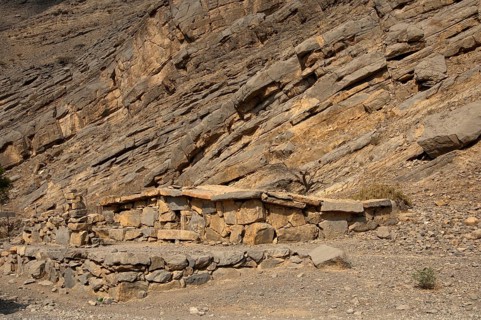 Bedouin stone house matching in colour and texture to the foot of a cliff in the mountains of Musandam