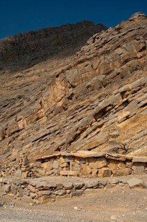 Bedouin stone house matching in colour and texture to the foot of a cliff in the mountains of Musandam