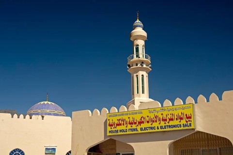 Sign of a business for household goods and electrical appliances in front of a mosque